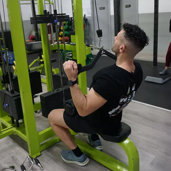 Hombre de mediana edad sentado utilizando máquina de gimnasio