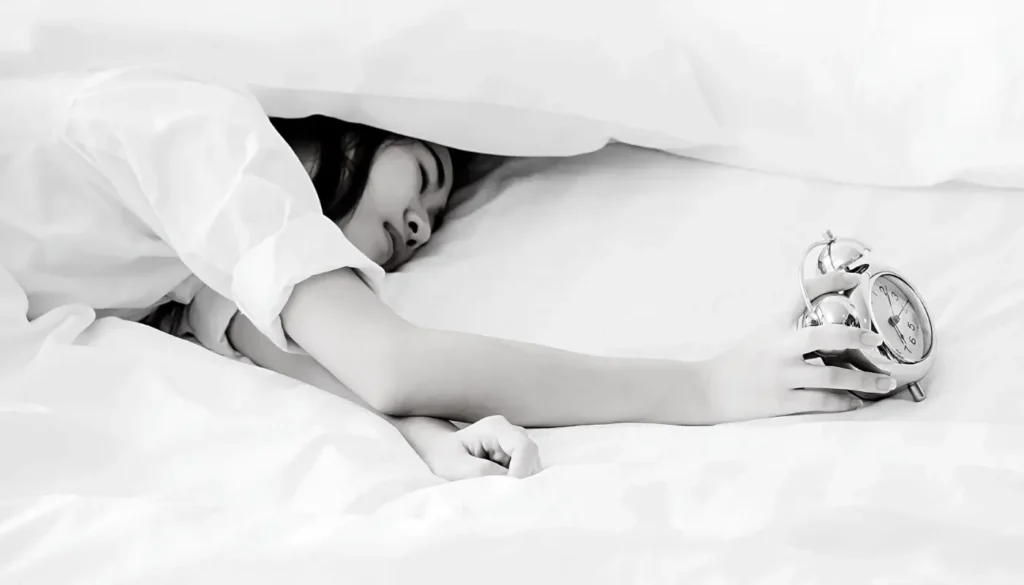 Foto de persona durmiendo con un reloj en mano
